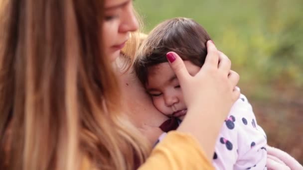 Młoda matka delikatnie przytula i głaszcze jej włosy córeczki w parku. - Materiał filmowy, wideo