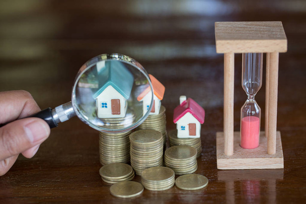 Stack coin and bar graph with grow,  Hand hold a magnifying glass searching for a new home, Loan for real estate or save money for buy a house to family in the future concept. - Photo, Image