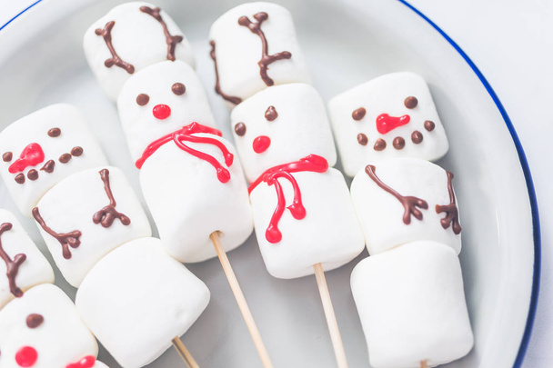 Close up view. Marshmallow snowmen and reindeer on sticks for hot chocate drink. - Фото, зображення