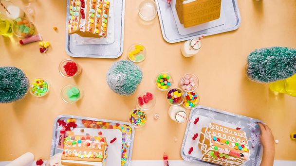 Flat lay. Kids decorating small gingerbread houses at the Christmas craft party. - Photo, Image