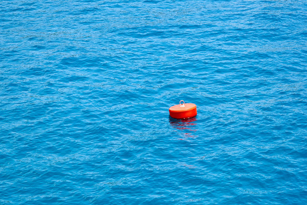 Κόκκινο σημαδούρα σχετικά με το γαλάζιο της θάλασσας. Μια σημαδούρα είναι μια κινητή συσκευή που μπορεί να έχει πολλούς σκοπούς. - Φωτογραφία, εικόνα