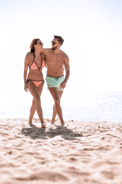 Young couple holding hands and walking on beach. - Valokuva, kuva