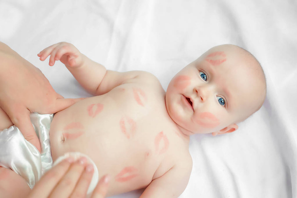 adorable niño con besos rojos en la piel sentado aislado sobre fondo blanco, Madre limpiando y limpia cuerpo bebé. vista superior. - Foto, Imagen