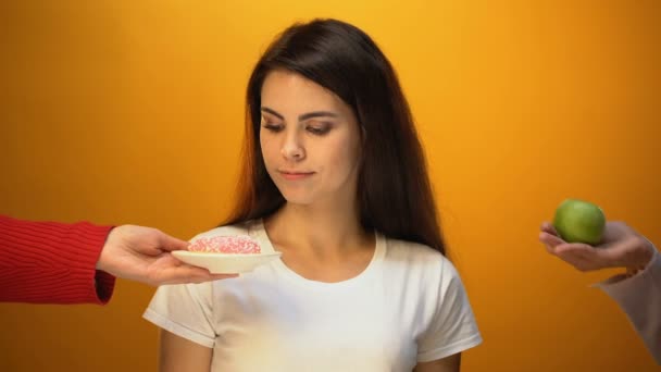 Girl eating apple instead of donut, healthy snack and vitamins vs sugary food - Felvétel, videó