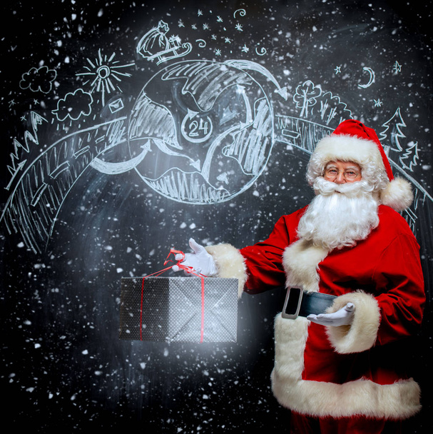 Un portrait du Père Noël avec une boîte cadeau debout dans une salle de classe près du tableau noir. Joyeux Noël et bonne année
! - Photo, image