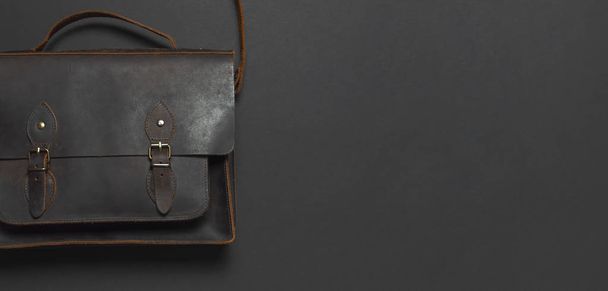 Έννοια της μόδας. Καφέ δερμάτινα Ανδρικά τσάντα σε μαύρο φόντο το top view επίπεδη θέσει με αντίγραφο χώρου. Χαρτοφύλακας για εργασία, μοντέρνα Αντρικά ρούχα, αξεσουάρ επιχειρηματίας επιχειρησης - Φωτογραφία, εικόνα