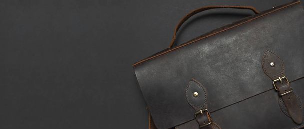 Έννοια της μόδας. Καφέ δερμάτινα Ανδρικά τσάντα σε μαύρο φόντο το top view επίπεδη θέσει με αντίγραφο χώρου. Χαρτοφύλακας για εργασία, μοντέρνα Αντρικά ρούχα, αξεσουάρ επιχειρηματίας επιχειρησης - Φωτογραφία, εικόνα