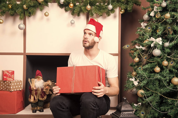 Guy with serious face in santa hat hold present box - Zdjęcie, obraz