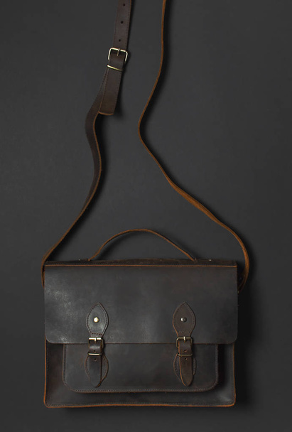Модная концепция. Brown leather men 's bag on black background top view flat lay with copy space. Портфель для работы, Аксессуары бизнесмен, стильная мужская одежда, бизнес-фон
 - Фото, изображение