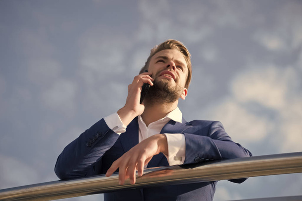 Businessman talk on smartphone. Man with mobile phone on blue sky. Boss in blue suit on sunny outdoor. Business communication, new technology and sms. Modern life and business lifestyle - Photo, image