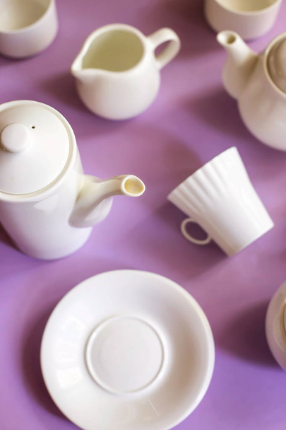 Witte stijlvolle minimalistische gerechten voor koffie en thee op een paarse lichte achtergrond. Tafelgerei-Concept. Bovenaanzicht - Foto, afbeelding