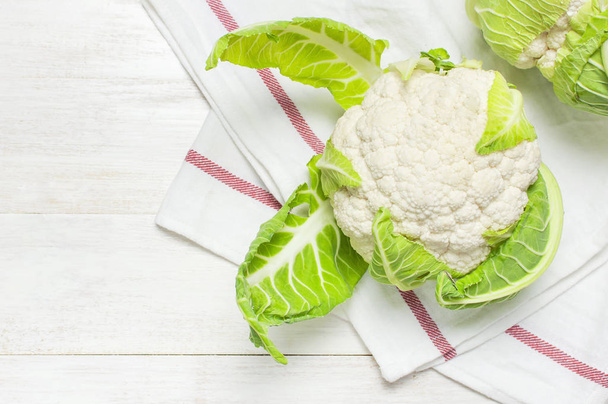 Fresh raw cauliflower, kitchen towel on rustic white wooden background top view flat lay copy space. Cooking, healthy wholesome food, vegetable, diet concept - Valokuva, kuva