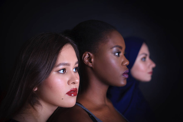 Макияж. Портрет трех женщин. Арабские, азиатские и афро-американские женщины позируют в студии на чёрном фоне. Мода, красота, глэм, молодость
. - Фото, изображение