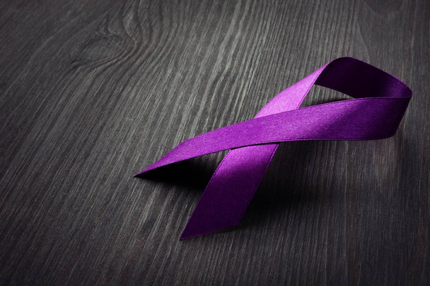 Purple awareness ribbon on a desk. Pancreatic cancer. - 写真・画像