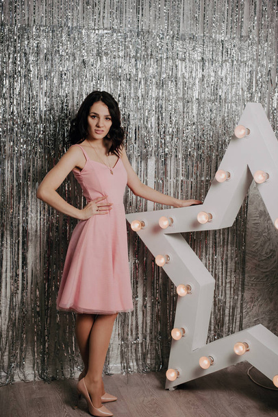 Young pretty Caucasian girl in a pink dress on a background of Christmas decor - Foto, immagini