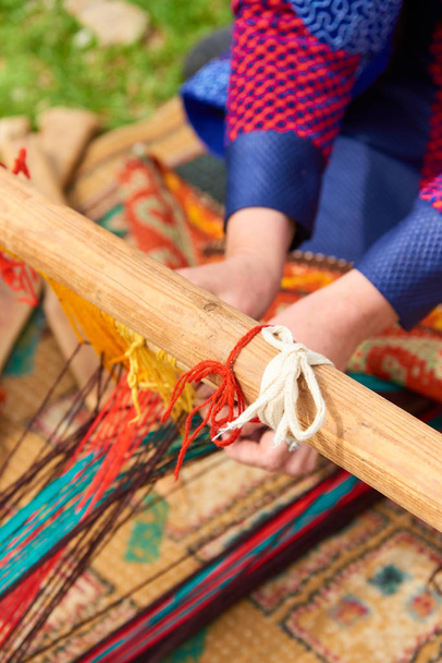 Tejido de alfombras.Tejido de alfombras hechas a mano primer plano. Las manos de las mujeres detrás de un telar
. - Foto, Imagen