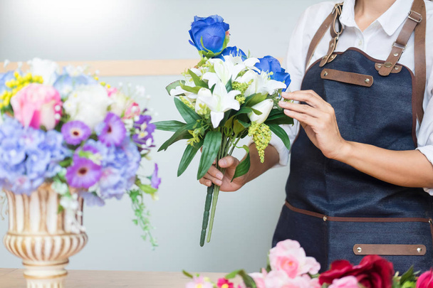Женщина-флорист за работой с помощью организации производства красивого искусственного жилета-букета в цветочном магазине, бизнесе, торговле и флористике ремесла и ручной работы концепции
 - Фото, изображение