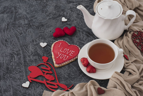 Романтический завтрак на День Святого Валентина. Печенье в форме сердца и чашка чая на сером столе с тканью. Вид сверху
  - Фото, изображение