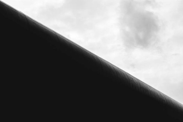 Діагональна футуристична будівля на тлі сірого меланхолійного неба. Чорно-білий
 - Фото, зображення