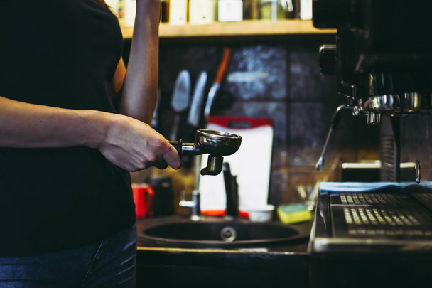 Female barista making a coffee near coffee machine in coze cafe in Lviv, Ukraine. Daily working atmosphere - Photo, image
