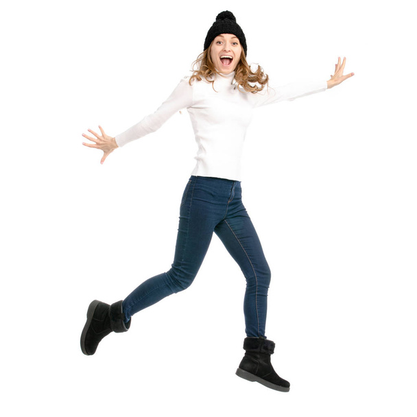 Beautiful woman in sweater jeans hat cold showing of positive emotions runs jumping - Foto, afbeelding
