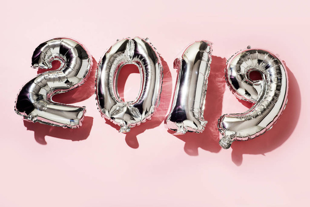 algunos globos plateados en forma de número que forman el número 2019, como el nuevo año, sobre un fondo rosa
 - Foto, imagen
