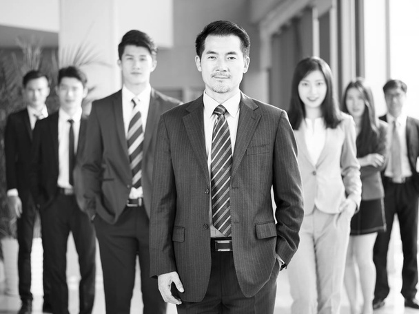 портрет команды успешных азиатских бизнесменов и бизнесвумен, смотрящих в камеру, черно-белый
. - Фото, изображение
