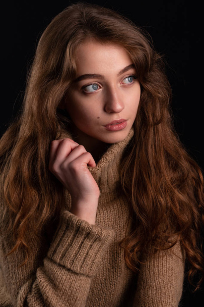 Retrato de cerca de una joven en un suéter sobre fondo oscuro
 - Foto, Imagen