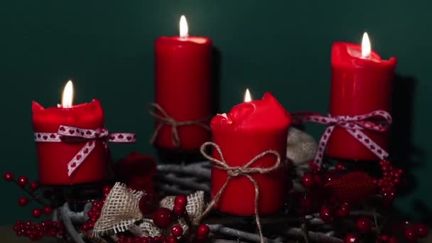 Moderni joulun seppele, jossa on neljä punaista kynttilää puupinnalla vihreällä taustalla
 - Materiaali, video