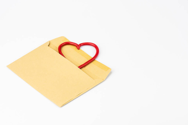 À esquerda, em um fundo branco, close-up, é um envelope de papel para letras. Do envelope olha para o coração, moldura. Parabéns pelo Dia de São Valentim. Espaço de cópia
 - Foto, Imagem