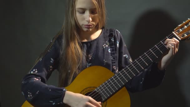 Girl play guitar. Studio light. Dark background. - Materiał filmowy, wideo