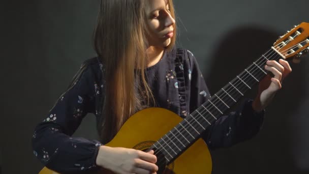 Girl play guitar. Studio light. Dark background. - Materiał filmowy, wideo