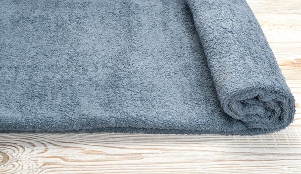graue Hotel gerollte Handtuchwellen Textur oder Material in Nahaufnahme. neue Frottee-Baumwollhandtücher oder weiches Waschlappen auf Holz-Hintergrund - Foto, Bild
