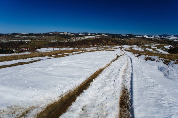 Spring landscape. Car tracks on thick snow on sunny day - Fotó, kép