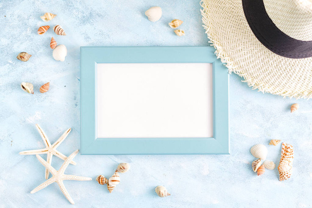 Top view flat lay summer mockup: empty blue photo frame, seashells, straw hat and starfish on blue background. Vacation concept. Space for lettering - Fotografie, Obrázek