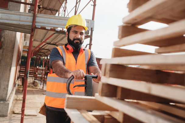 Latino Manual Worker With Forkift Pallet Stacker In Construction Site - Photo, image