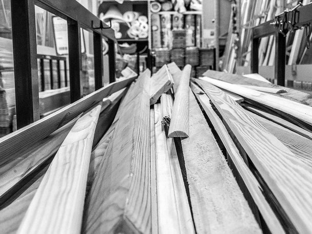 As placas de construção naturais serradas a preto e branco de madeira colam troncos com nós em um rack em uma serraria em uma loja. O fundo
 - Foto, Imagem