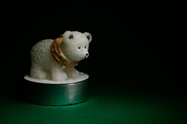 Симпатичная фигурка белого медведя на темно-зеленом фоне
 - Фото, изображение