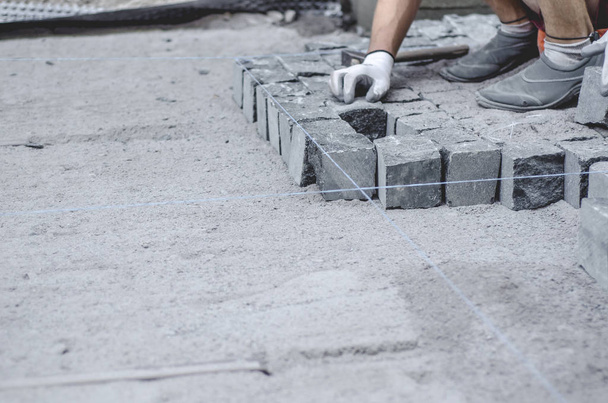 Trabajador pone baldosas de granito gris pavimento en el sitio marcado. Disposición del entorno urbano. Reparación de carreteras urbanas
 - Foto, Imagen