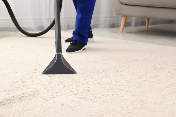 Man removing dirt from carpet with vacuum cleaner indoors, closeup. Space for text - Valokuva, kuva
