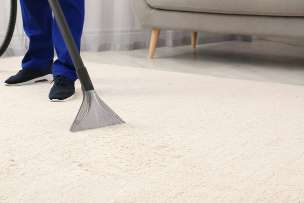 Man removing dirt from carpet with vacuum cleaner indoors, closeup. Space for text - Valokuva, kuva