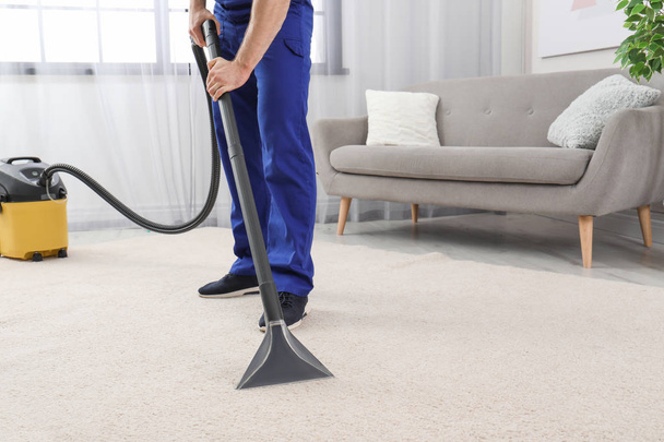 Man removing dirt from carpet with vacuum cleaner indoors, closeup. Space for text - Foto, Imagem