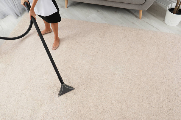 Chambermaid removing dirt from carpet with vacuum cleaner indoors, closeup. Space for text - Φωτογραφία, εικόνα