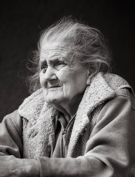 Старость и образ жизни. Черно-белый портрет очень старой и уставшей морщинистой женщины на улице. Очень старая серая женщина лицо крупным планом портрет. Процесс старения - очень пожилые женщины
 - Фото, изображение