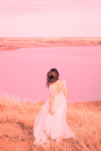 Woman bride in wedding dress near the lake, from behind. The concept of fashion colors 2019, living coral - Foto, immagini