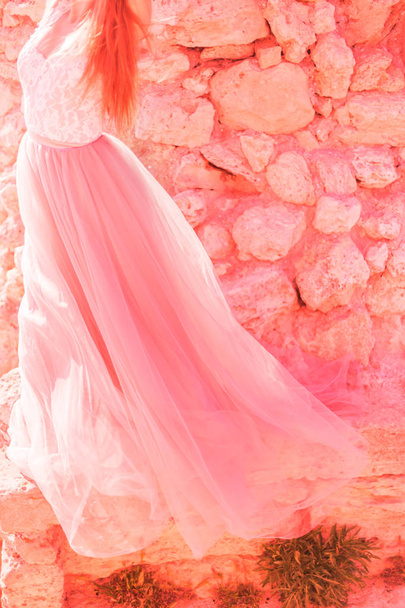 The bride in a pink wedding dress on the background of stones in nature. The concept of fashion colors 2019, living coral - Foto, Imagem