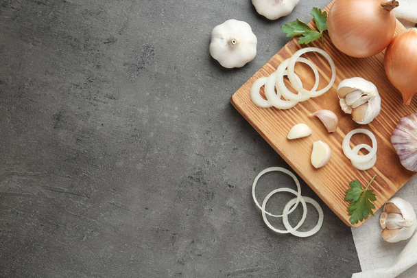 Flat lay composition with garlic, onions and space for text on grey background - Foto, imagen