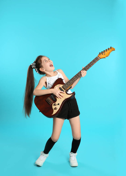 Cute little girl playing guitar on color background - Fotografie, Obrázek