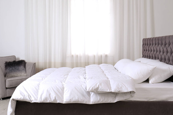Large comfortable bed in light room. Stylish interior - Zdjęcie, obraz