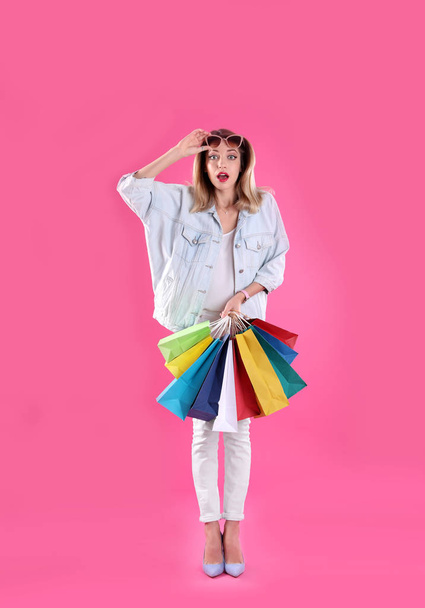 Beautiful young woman with shopping bags on color background - Фото, изображение